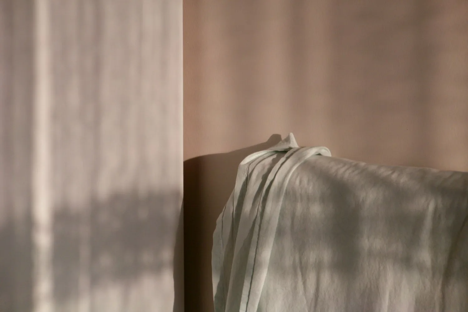 Soft daylight falling across a linen sheet and a warm plaster wall