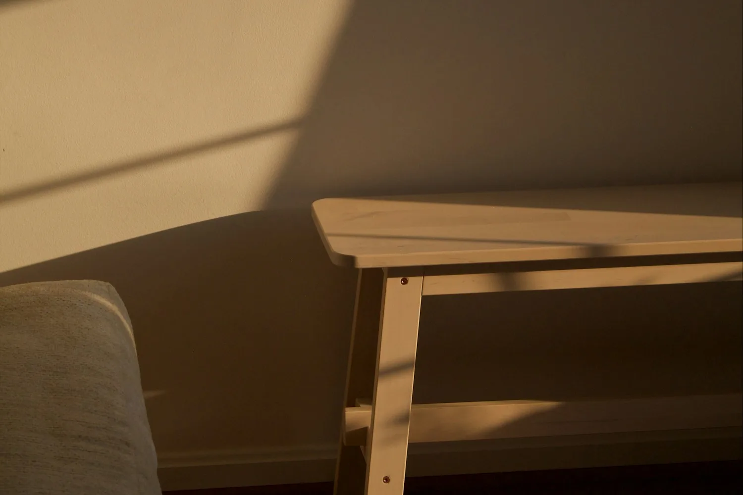An empty wooden bench in a quiet room lit by low golden evening light