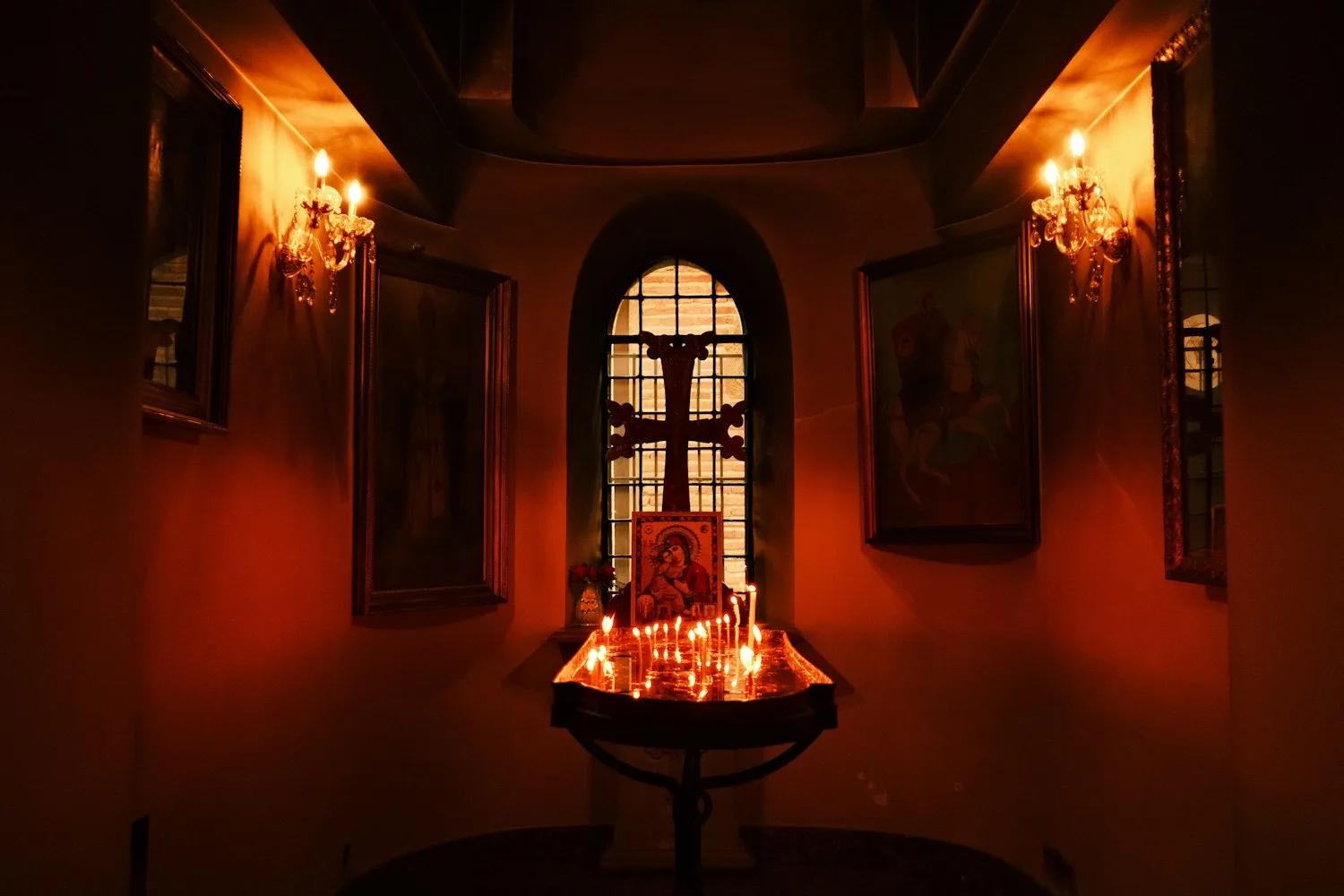 Candles lit before an icon and a cross in a quiet chapel, ready for evening Taizé prayer